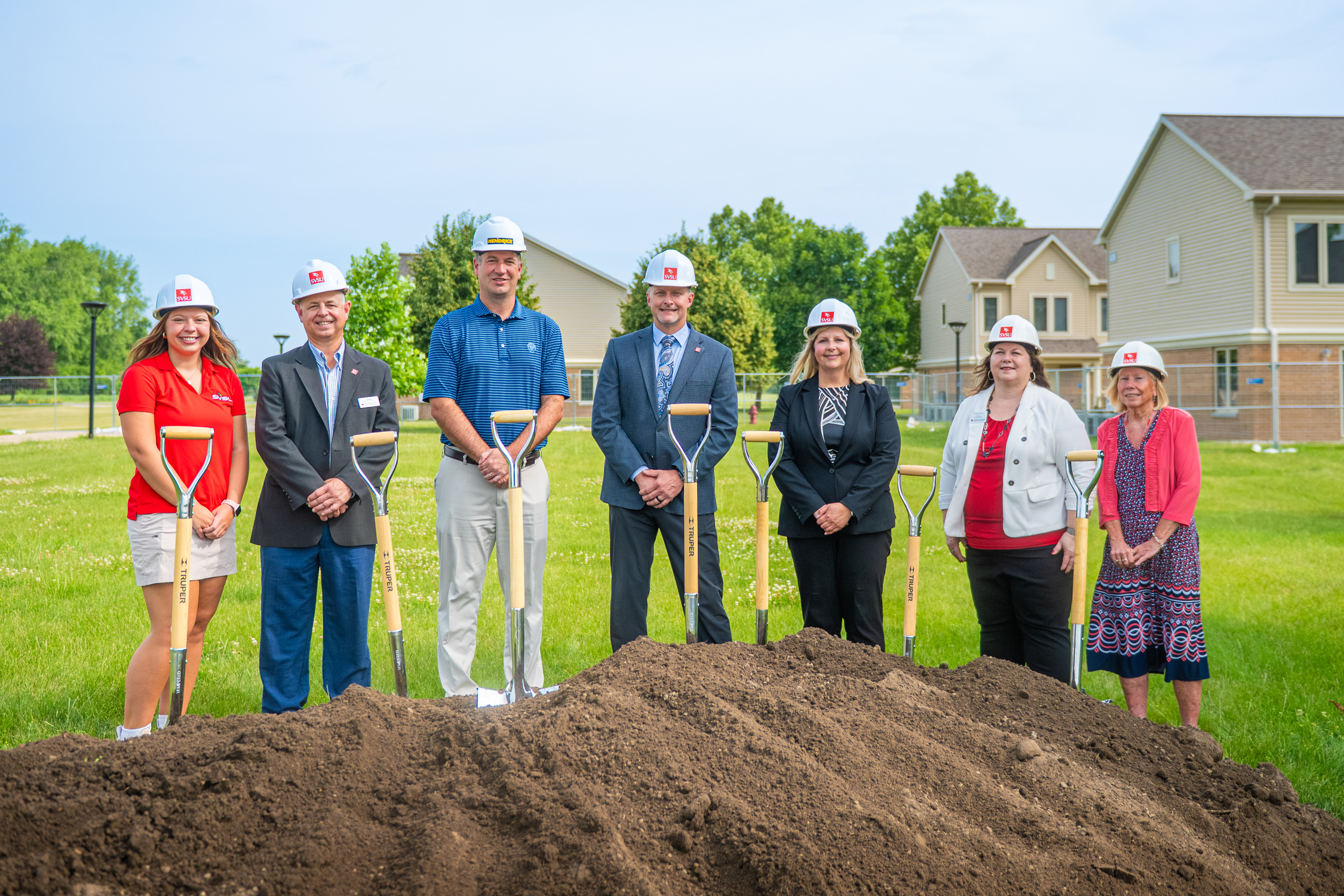 group of people with shovels at dirt pile